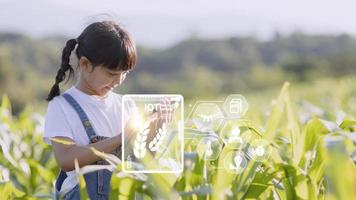 The little girl uses a tablet to analyze the growth of plants in the agricultural plot and visual icon., the agricultural technology concept. smart farming learning Concept photo