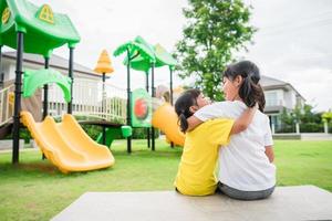 Child playing on outdoor playground. Kids play on school or kindergarten yard. Active kid on colorful slide and swing. Healthy summer activity for children. photo