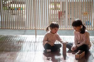 two Asian girls playing wooden stacks at home photo