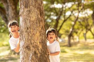 little girl is playing hide-and-seek hiding face in the park photo