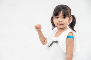 Asian little girl showing his arm after got vaccinated or inoculation, child immunization, covid delta vaccine concept photo