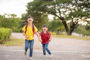 lindos niños asiáticos tomados de la mano mientras van a la escuela foto