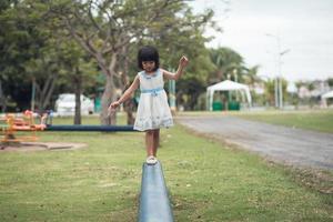 niña caminando sobre un tronco en el parque.en el equilibrio foto