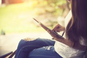 Young girl works on the tablet on the internet and goes to the train, ipad surfing, woman using smartphone, holding tablet in hand, send answer texts, travel in train, office manager, hipster photo