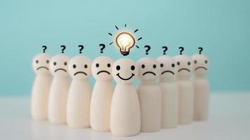 Smiley wooden human with light bulb and others human with question mark for creative thinking and problem solving solution concept. photo