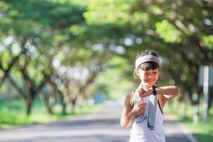 happy child girl running in the park in summer in nature. warm sunlight flare. asian little is running in a park. outdoor sports and fitness, exercise and competition learning for kid development. photo