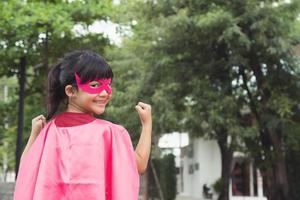 Funny little girl playing power superhero over white background. superhero concept. photo