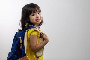 Asian young girl showing her arm with yellow bandage after got vaccinated or inoculation, child immunization, covid delta vaccine concept photo