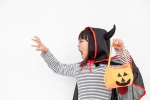 Funny Halloween Kid Concept, little cute girl with costume Halloween ghost scary he holding orange pumpkin ghost on hand, on white background photo