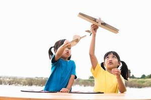 Two little kids playing with cardboard toy airplane in the park at the day time. Concept of happy game. Child having fun outdoors. photo