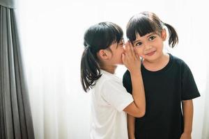 pequeños hermanos asiáticos felices compartiendo secretos foto