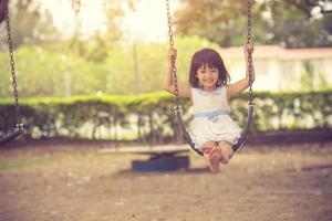 Little girl swinging on swing at park photo