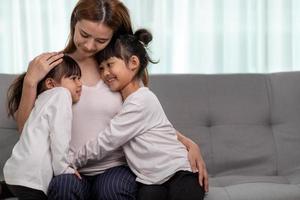 people and family concept - happy smiling girl with mother hugging on sofa at home photo