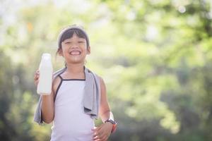 Cute asian little child girl is drinking a milk, soft focus photo