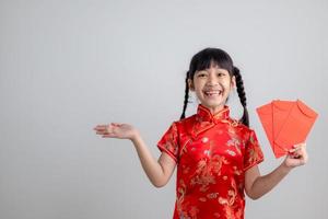 Happy Little Asian girl in Chinese traditional dress smiling and holding a red envelope. Happy Chinese new year concept. photo