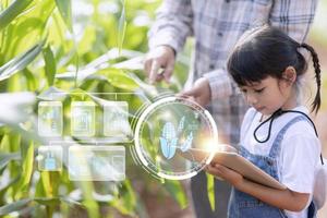 The little girl uses a tablet to analyze the growth of plants in the agricultural plot and visual icon., the agricultural technology concept. smart farming learning Concept photo