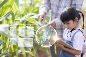 The little girl uses a tablet to analyze the growth of plants in the agricultural plot and visual icon., the agricultural technology concept. smart farming learning Concept photo