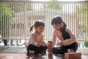 two Asian girls playing wooden stacks at home photo