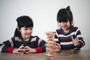 alegre chica asiática jugando con bloques de construcción de madera. divertirse y aprender creatividad. concepto de niño inteligente. foto