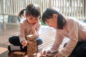 two Asian girls playing wooden stacks at home photo