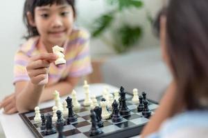 Little sibling girl playing chess at home. photo