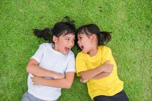 primer plano de niños asiáticos felices tirados en la hierba verde foto