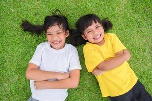 Closeup of happy asian children lying on the green grass photo