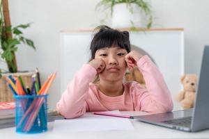 Unhappy little Caucasian girl child sit at table at home feel lazy unmotivated doing homework assignment. Upset distressed small 7s kid prepare school task, learn study with books. Education concept. photo
