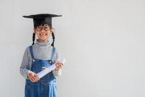 feliz niño de la escuela asiática graduado en gorra de graduación foto