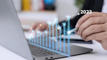 Businessman analyzes profitability of working companies with digital augmented reality graphics, positive indicators in 2023, businessman calculates financial data for long-term investments. photo