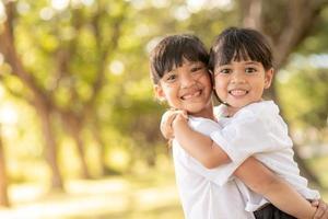 dos niñas asiáticas que se abrazan con amor en el jardín i foto