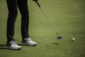 Golf player at the putting green hitting ball into a hole photo