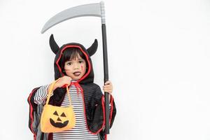 Children girl wearing mysterious Halloween dress holding a scary pumpkin and sickle. photo