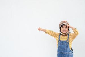 sueños de vuelo niña pequeña jugando con un sombrero de piloto sobre fondo blanco foto