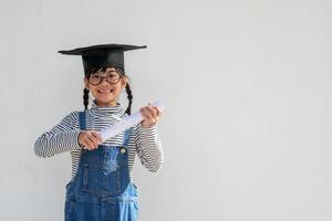 feliz niño de la escuela asiática graduado en gorra de graduación foto