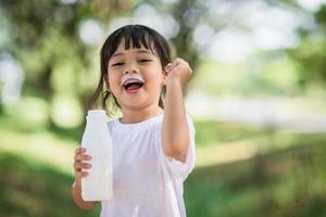 Cute asian little child girl is drinking a milk, soft focus photo