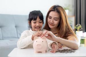 Family Savings. Mother Teaching Little Daughter How To Save Money Holding Piggybank photo