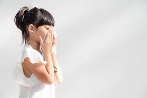 niña asiática enferma con estornudos en la nariz y tos fría en papel tisú porque es débil o tiene virus y bacterias del clima polvoriento foto