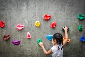 little girl climbing a rock wall photo