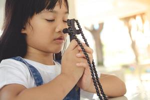 niña asiática rezando sosteniendo la cruz, concepto cristiano. foto