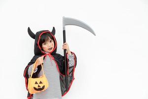 niña con un misterioso vestido de halloween sosteniendo una calabaza y una hoz aterradoras. foto