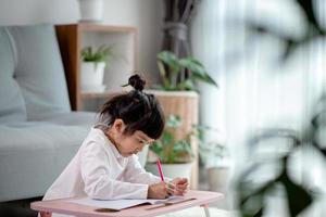 children, education and learning concept - happy girl writing to notebook at home photo