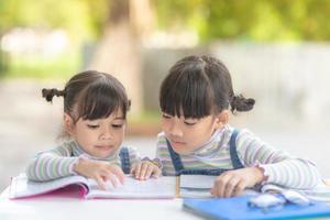 dos estudiantes niñas asiáticas leyendo el libro en la mesa foto