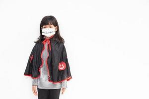 Asian little girl in a Halloween costume in a medical mask . Halloween with safety measures from Covid-19 photo