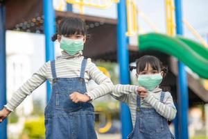 new normal lifestyle, social distancing concept. happy kids wearing face masks having fun on at playground protect coronavirus covid-19, photo