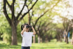 Happy child girl playing with binoculars. explore and adventure concept photo