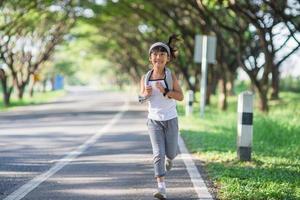 happy child girl running in the park in summer in nature. warm sunlight flare. asian little is running in a park. outdoor sports and fitness, exercise and competition learning for kid development. photo