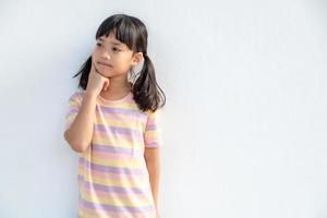 Thoughtful little girl child touch chin with finger thinking or considering, pensive lovely daughter making decision imagining idea posing isolated on white background photo