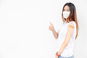 Asian Women Show Bandage On Arm. Happy Asian Woman Feels Good After Received Vaccine On White Background.Thumb up. photo