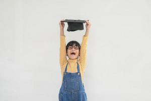 children girl wearing a graduate cap over white background very happy and excited doing winner gesture with arms raised, smiling and screaming for success. Celebration concept. photo